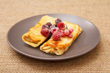Homemade pancakes filled with cottage cheese and topped with frozen raspberries and blackberries on plate