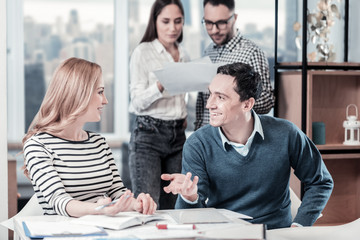 Obraz premium Pleasant conversation. Clever nice-looking friendly colleagues sitting in the office near friends gesticulating and communicating.
