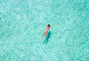 Attraktive Frau im Bikini treibt auf türkisem tropischen Wasser und entspannt sich
