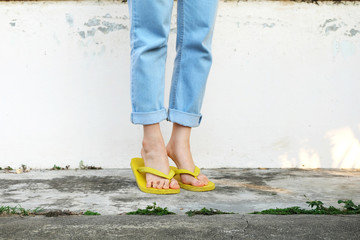 Yellow Sandals. Woman Wearing Flip Flops and Blue Jeans Standing on Old Cement Floor Background Great for Any Use.