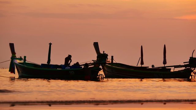 Travel video silhouette long tail boat and The fisherman are maintenance ship. After the boats go out, such as catching the fish. Trips are made every day with  golden light of the Sun  before sunset