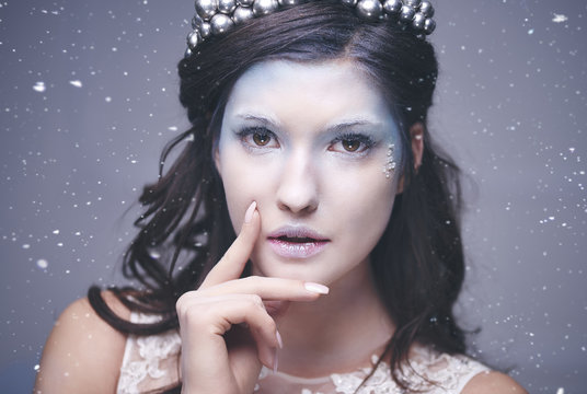 Attractive snow queen among snow falling ..