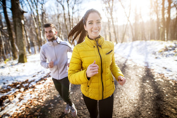 Couple sportif d& 39 athlètes actifs courant avec une forte persistance sur la route dans la nature hivernale le matin.