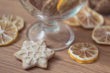 A fragrant Christmas cookie rests on a wooden table next to a glass vase