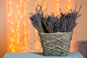 Bunches of lavender flowers in a wicker basket. lights garland in the background