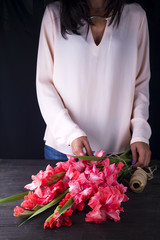 women's hands create a bouquet of flowers of gladiolus