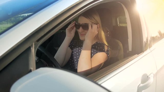 Slow motion footage of young female driver wearing sunglasses driving car