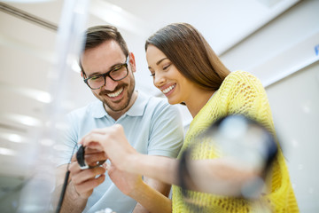 Portrait of happy satisfied smiling young couple in love holding a wristwatch in a tech store.