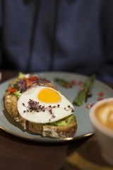 Benedict eggs served on a toast on a grey plate and blue background