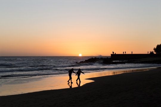 ni&ntilde;os jugando en la playa en un atardecer