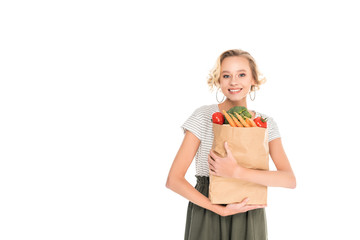 attractive happy young woman holding grocery bag and looking at camera isolated on white