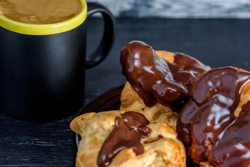 Coffee and chocolate eclairs on a dark wooden background