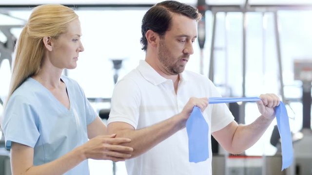 Physiotherapist and patient using resistance band