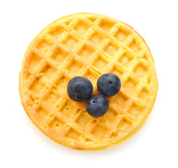 A round waffle and blue berries on a white background