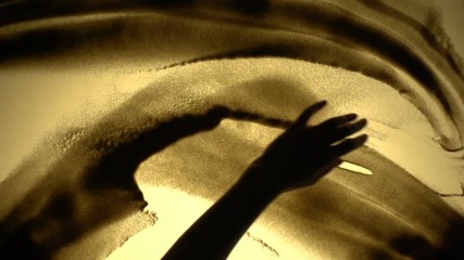 Abstract footage of hand playing with sand on a sand art table in slow motion