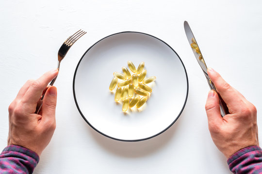 Man Eats Capsules Of Fish Oil From A Plate