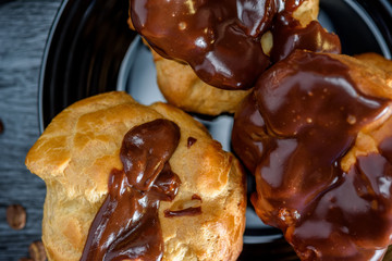 Coffee and chocolate eclairs on a dark wooden background