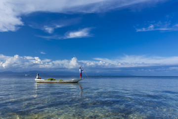 Farmers returning home with a traditional boat full of daily algae harvest  at crystal clear waters of Nusa Lembongan, Bali
