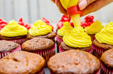 The process of decorating muffins with yellow cream, prepared on the basis of butter.
