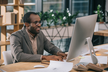Obraz premium african american architect working with computer and blueprints in office