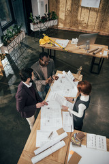 high angle view of team of architects discussing building plans