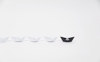 creative black paper ship among white. concept leadership different.