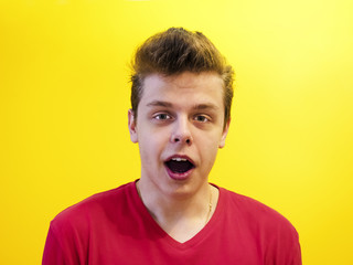 Portrait of a young man with a shocked facial expression isolated on a yellow background