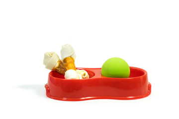 Pet supplies about snack bone in bowl with rubber toy isolated on white background.