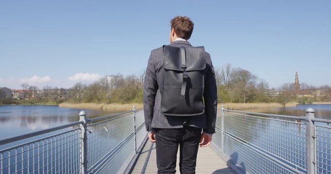 Young urban professional business man walking to work wearing backpack wearing backpack. Businessman in 30s in Copenhagen, Denmark, Scandinavia.