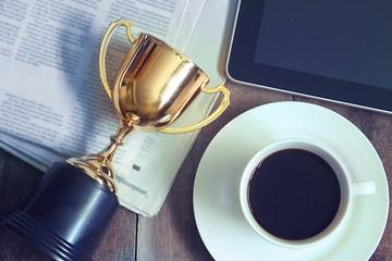  Topview Gold trophy prize with coffee and news paper and tablet on the table , business concept.