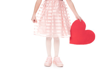 cropped shot of little child in pink dress holding red heart symbol isolated on white