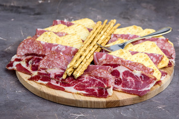 Obraz premium Food Tray With Delicious Salami Pieces of Sliced Ham and Crackers and Bread Sticks Meat Plate