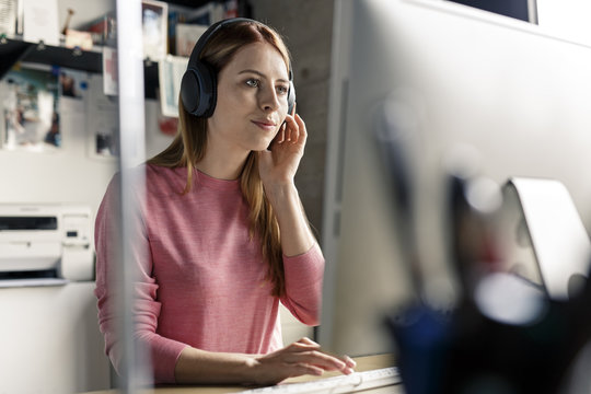 Portrait Of Young Woman Wearing Headphones At Desk At Home