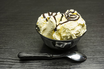 Vanilla ice cream with chocolate in a black bowl.