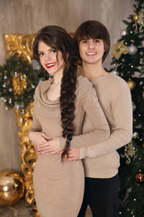 Obraz na płótnie Canvas Christmas portrait of young teen couple hugging wearing in beige clothes smiling and having fun at camera.