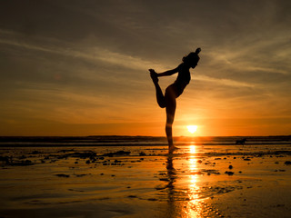 Frau macht Yoga am Strand bei Sonnenuntergang