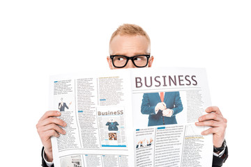 young man in eyeglasses hiding behind business newspaper isolated on white