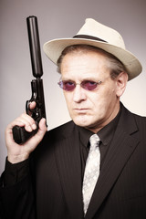 Stylish man armed with pistol with silencer in style of mob criminal
