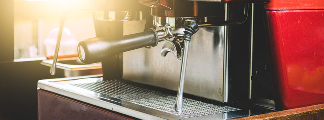 A professional Barista Use a coffee machine to BREW coffee at a customer order at The coffee shop is decorated in a retro style, with sunlight.