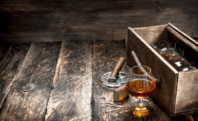 Cognac background. A bottle of cognac in a box with a glass and a cigar.