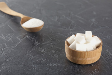 pieces of sugar in  bowl and spoon on  dark background