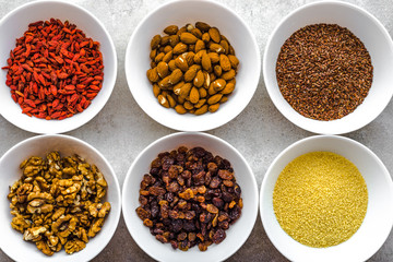 Vegetarian breakfast with healthy food selection, nuts, seeds, goji berries and other superfoods on table, flat lay, overhead