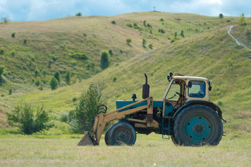 Old tractor on a meadow in summer. Farm in the village.