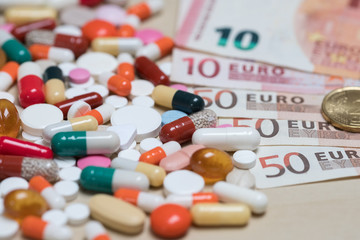 Different pills and banknotes are money euros. A symbol of expensive medical care and medical insurance.