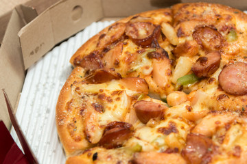 Close up of pizzas with variety of toppings and cheese in cardboard take out boxes with open lid