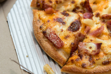Close up of pizzas with variety of toppings and cheese in cardboard take out boxes with open lid