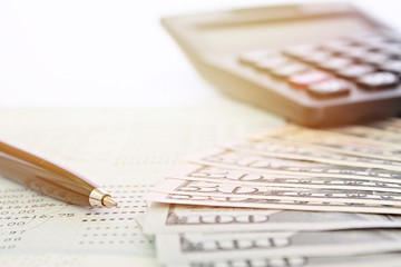 Business, finance, investment or money exchange background concept : American dollar cash money, calculator and savings account passbook or financial statement on table