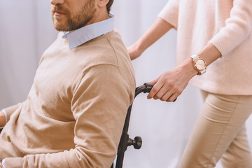 cropped image of wife carrying husband in wheelchair