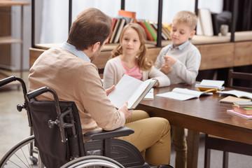 Obraz premium father on wheelchair teaching children at home