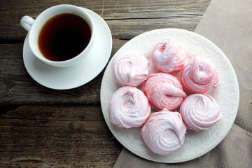 white ceramic cup with black coffee and marshmallow dessert on wooden table, top view